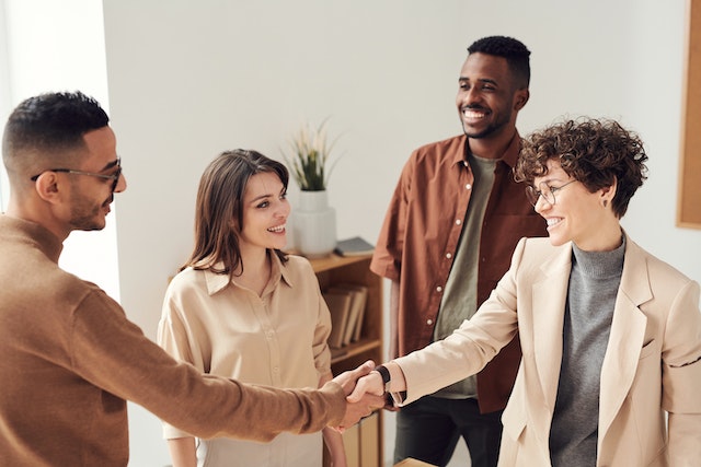 A group of four people greeting each other, two of them shaking hands