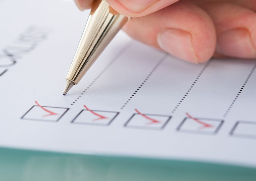 A landlord completes an end of tenancy cleaning checklist with a golden pen, marking red checkmarks on a page.