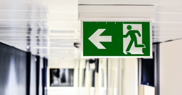 green emergency exit sign directing people to stairs