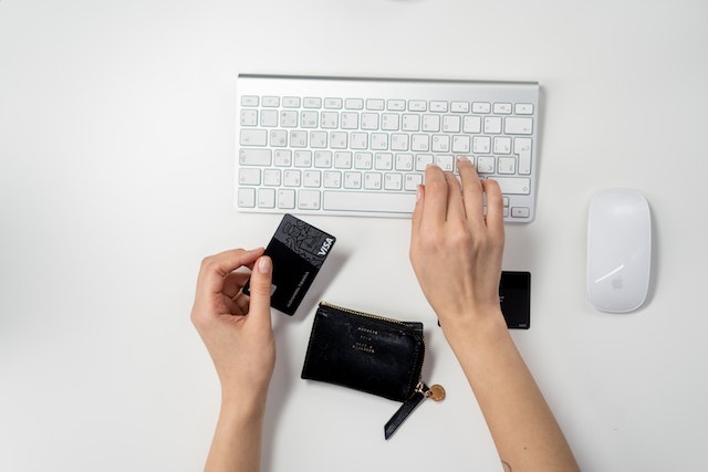 hand holdings a credit card and typing on a computer keyboard to make an online payment