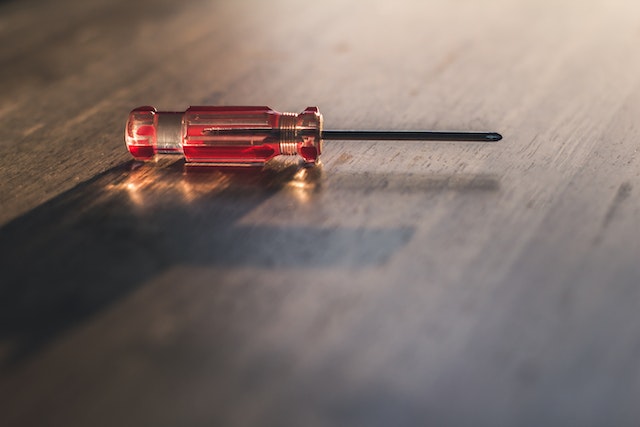 red screwdriver on dark wood floor